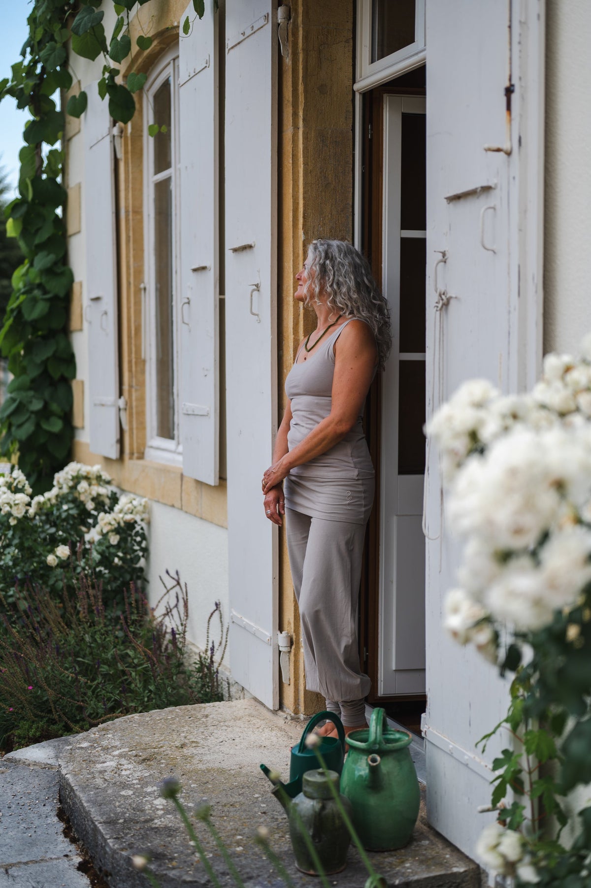 Woman in the taupe Sohang yoga top and pants in organic cotton, back on the mat